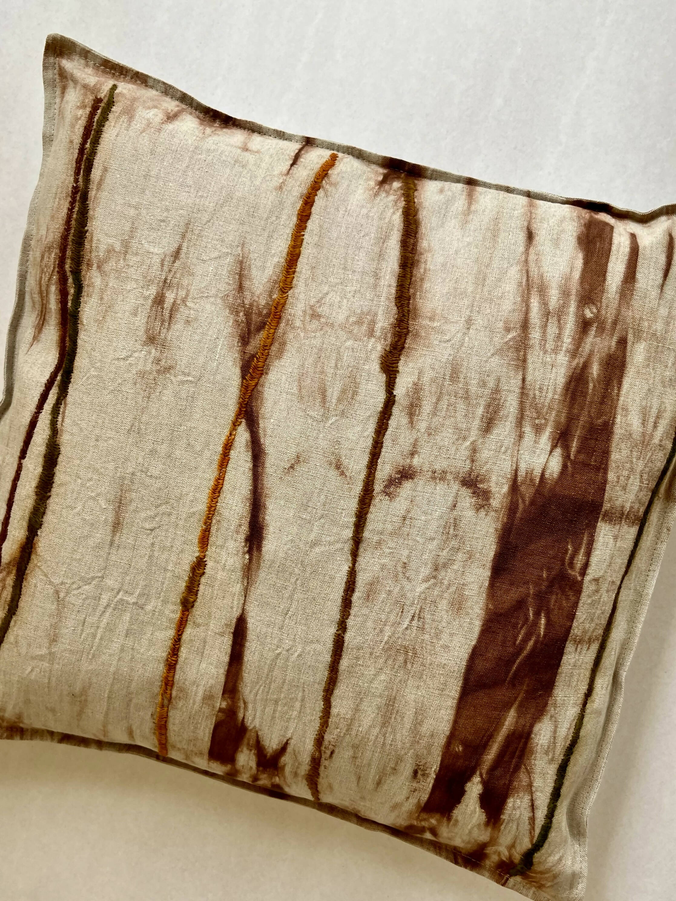 Funda de cojín lino con manchas bordadas que simulan troncos