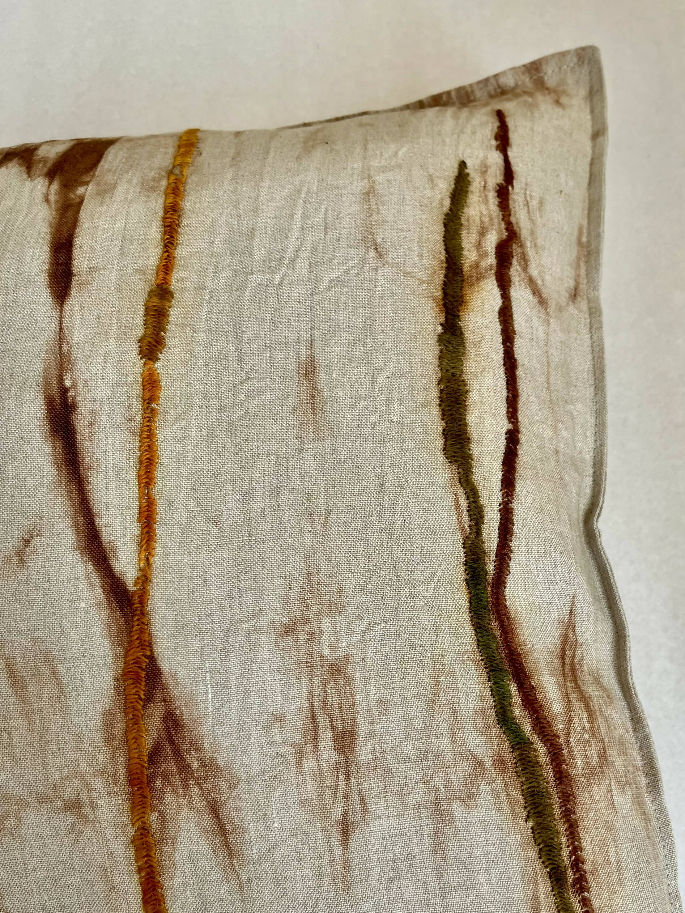 Funda de cojín lino con manchas bordadas que simulan troncos